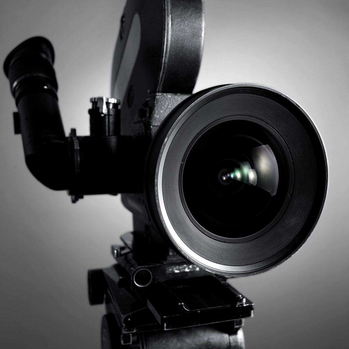 Professionelle Filmkamera mit großem Objektiv vor grauem Hintergrund