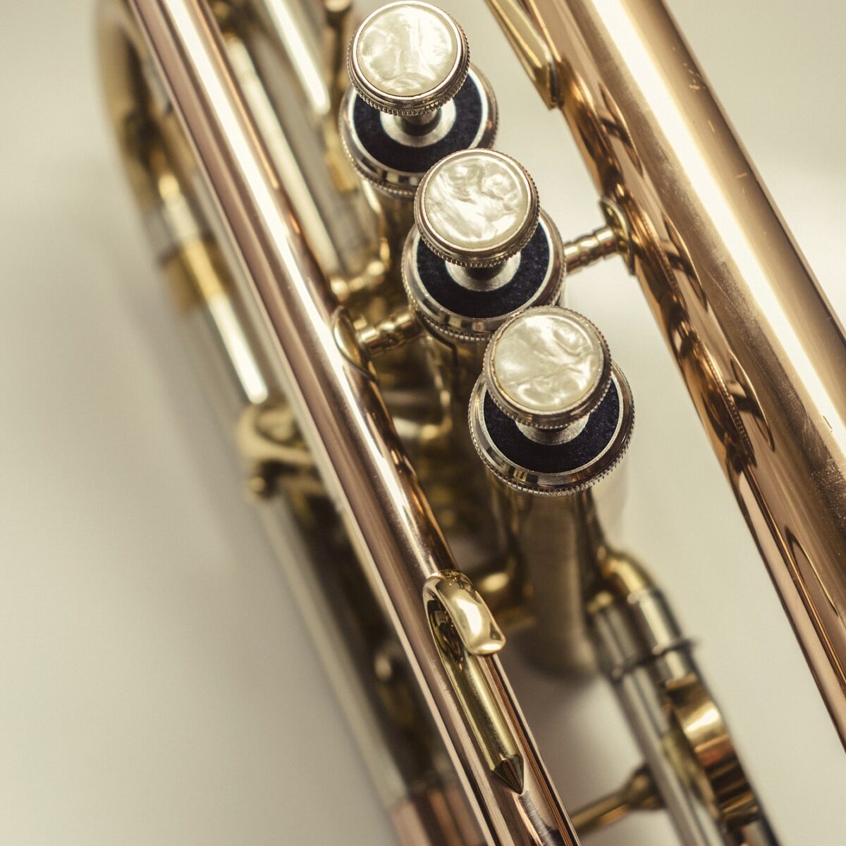 Detailaufnahme einer glänzenden Trompete mit Fokus auf die Perlmutt-verzierten Ventilknöpfe.