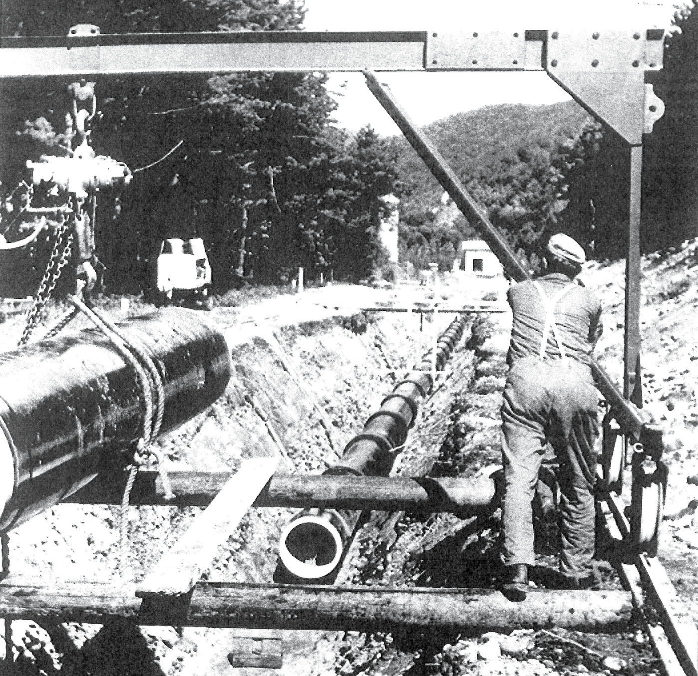 Schwarz-weiß-Aufnahme eines Arbeiters, der Wasserleitungsrohre verlegt