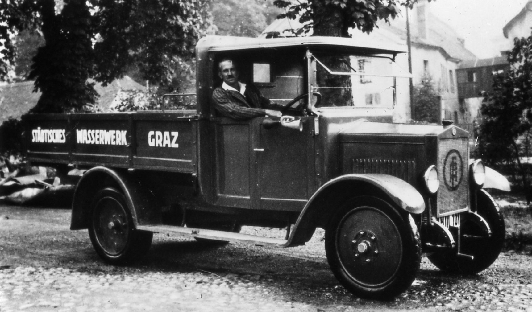 Schwarz-weiß-Aufnahme von Lastwagen der Wasserwirtschaft, Beifahrer schaut aus Fenster.