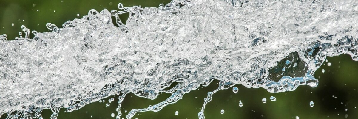 Nahaufnahme von spritzendem Wasser vor unscharfem, grünem Hintergrund.