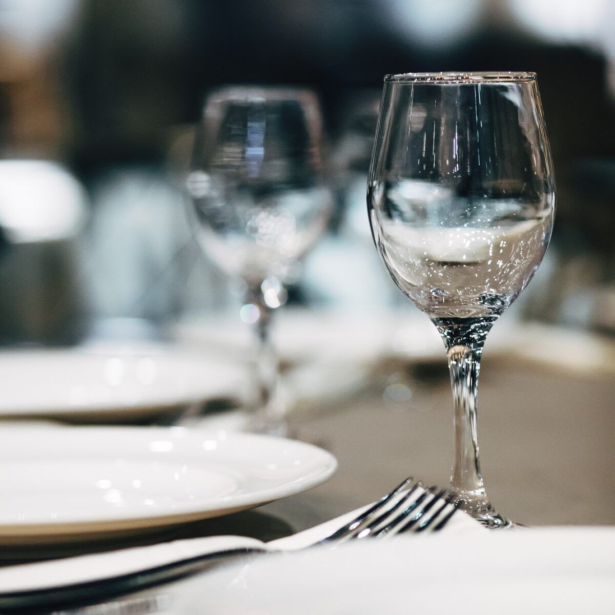 Eleganter gedeckter Tisch mit Weingläsern und Tellern in einem stilvollen Restaurantambiente.