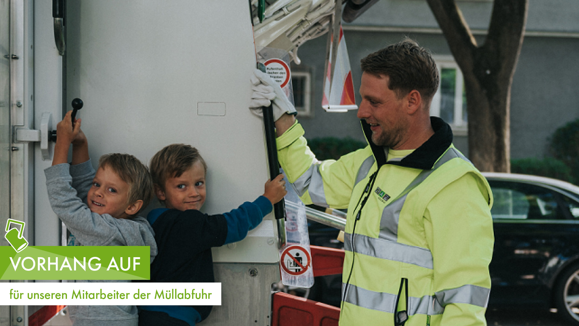 Mitarbeiter der Müllabfuhr zeigt zwei Kindern an Müllfahrzeug Details, beide lächeln fröhlich.