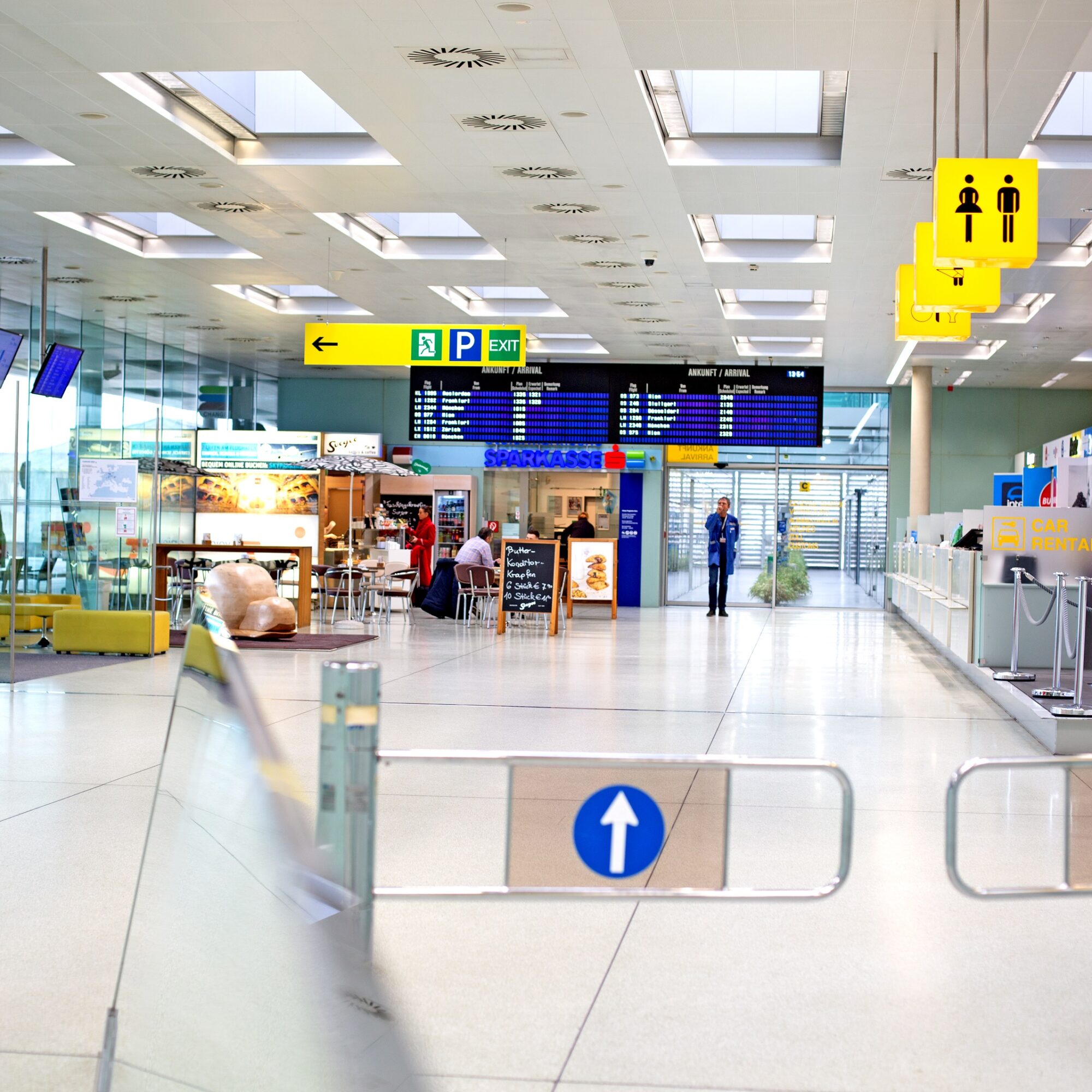 A view down the arrival hall at Graz Airport, with signs for "P - Exit" and "WC."