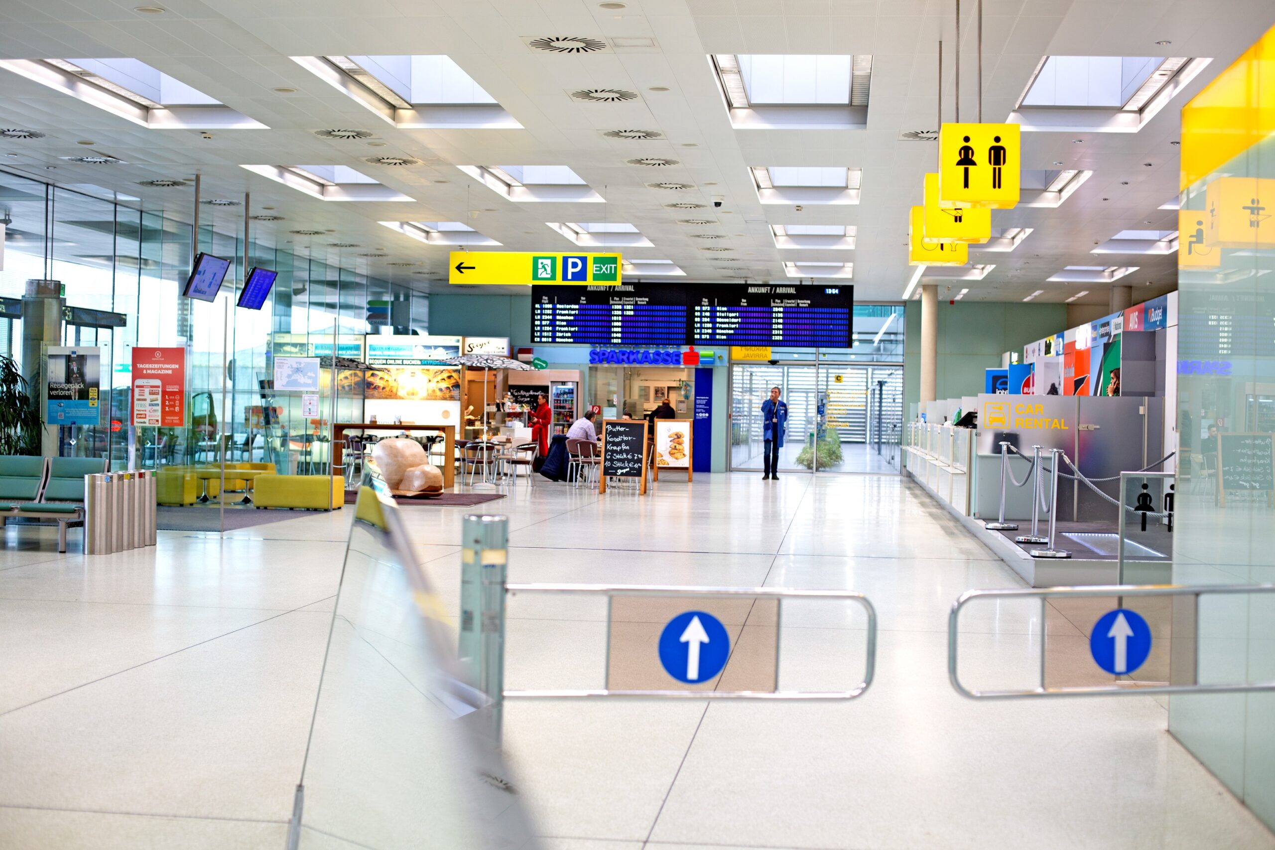 Innenansicht des Grazer Flughafenterminals mit Wegweisern, Anzeigetafeln und Schaltern.