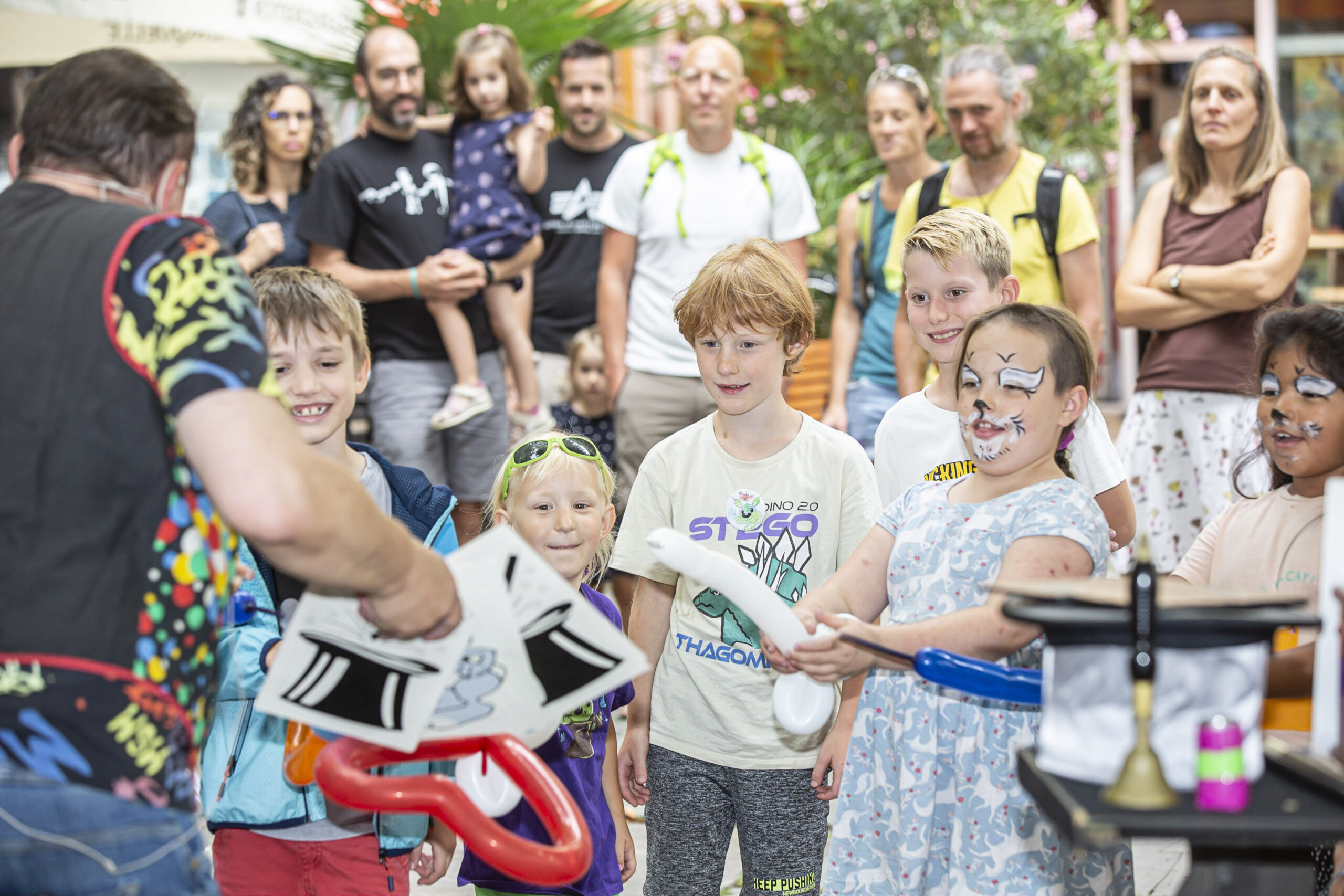 Kinder und Erwachsene schauen dem Zauberer bei einer Vorstellung zu bei der Veranstaltung "Auf die Plätze"