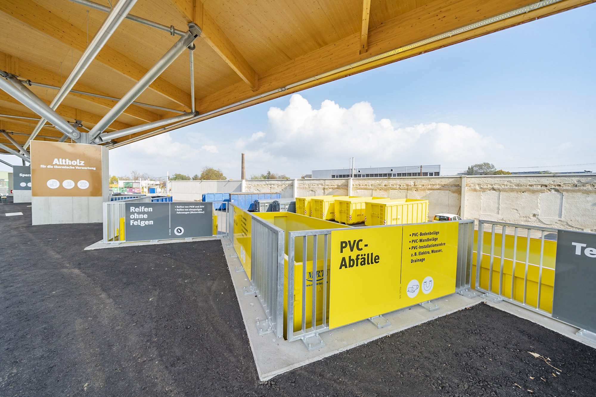 Recyclingstation mit Bereichen für Altholz, Reifen und PVC-Abfälle unter moderner Überdachung.