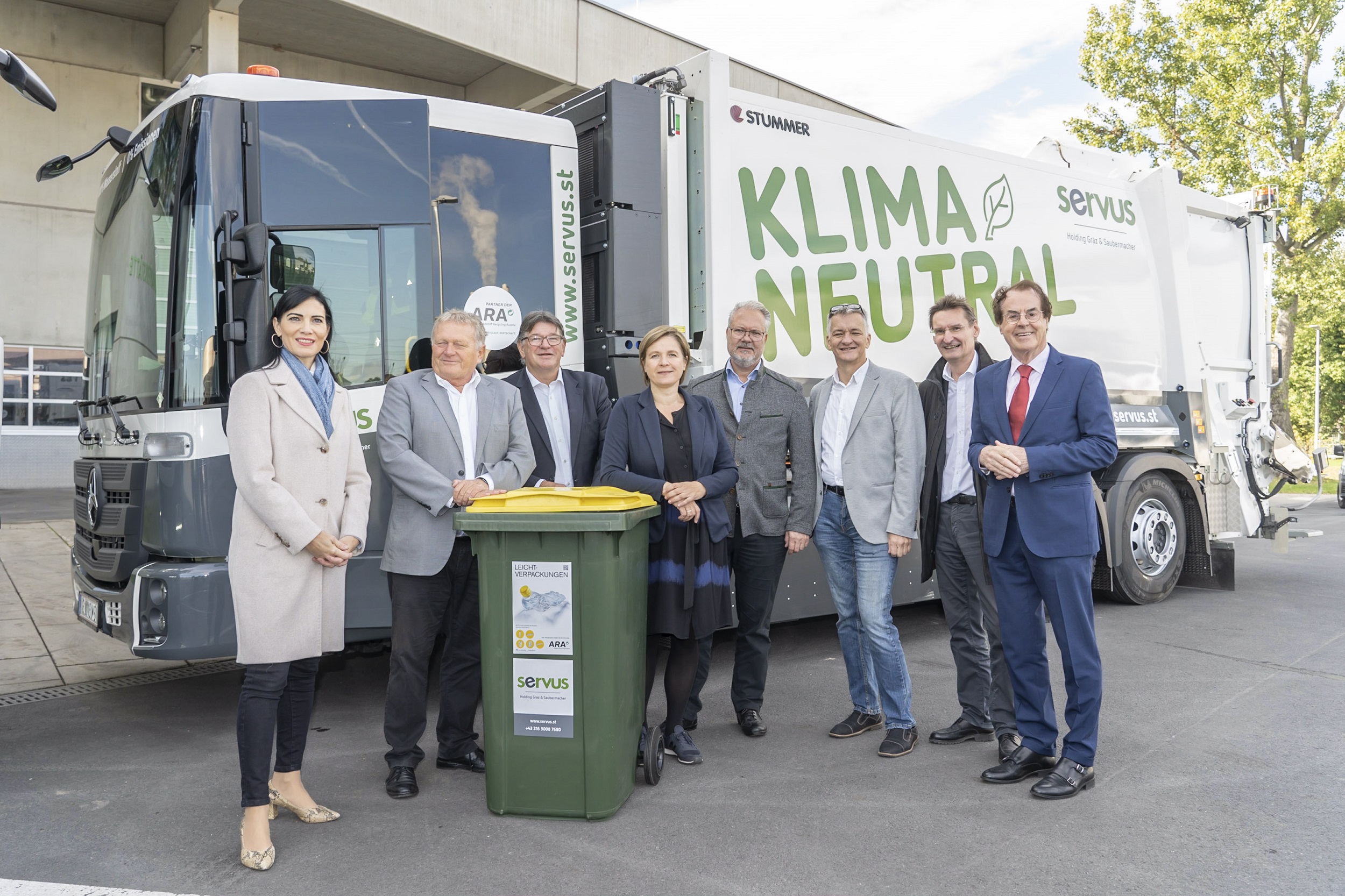 Gruppenfoto vor klimaneutralem Sammelfahrzeug mit Fokus auf Nachhaltigkeit und Umweltschutz.