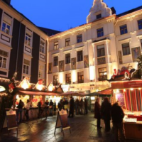 Adventmarkt am Glockenspielplatz mit stimmungsvoller Beleuchtung und geschmückten Ständen.