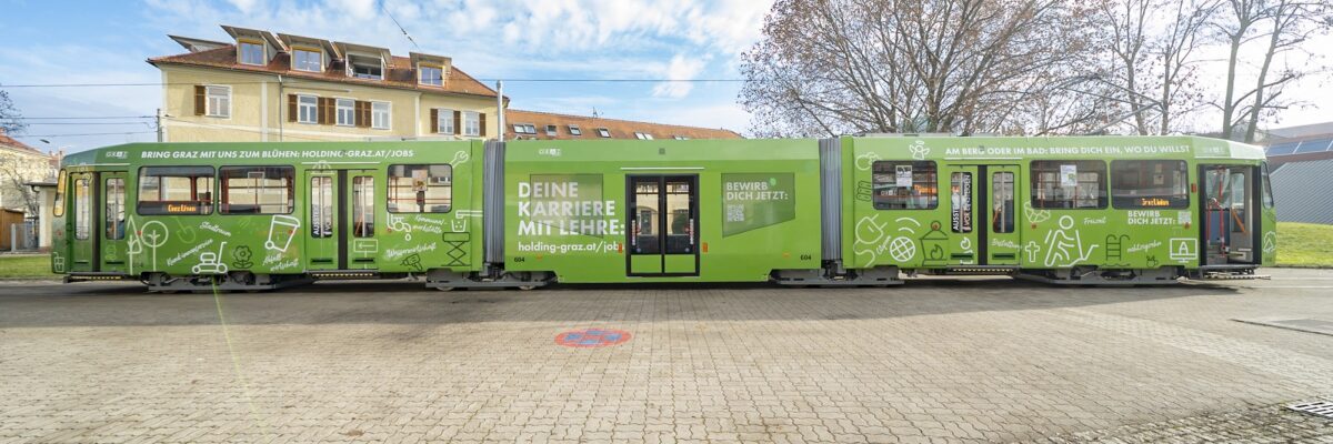 Grüne Straßenbahn mit Werbeaufschrift "Deine Karriere mit Lehre" und Website der Holding Graz.