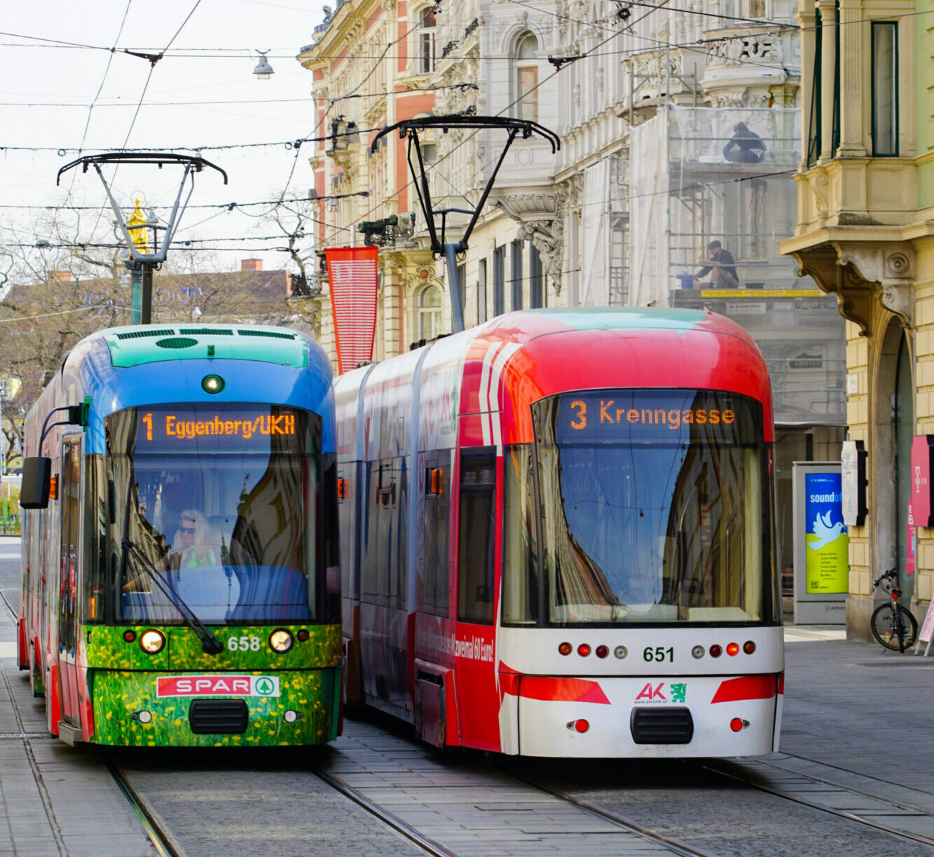 Zwei Straßenbahnen in Graz: Linie 1 Richtung Eggenberg/UKH und Linie 3 Richtung Krenngasse.