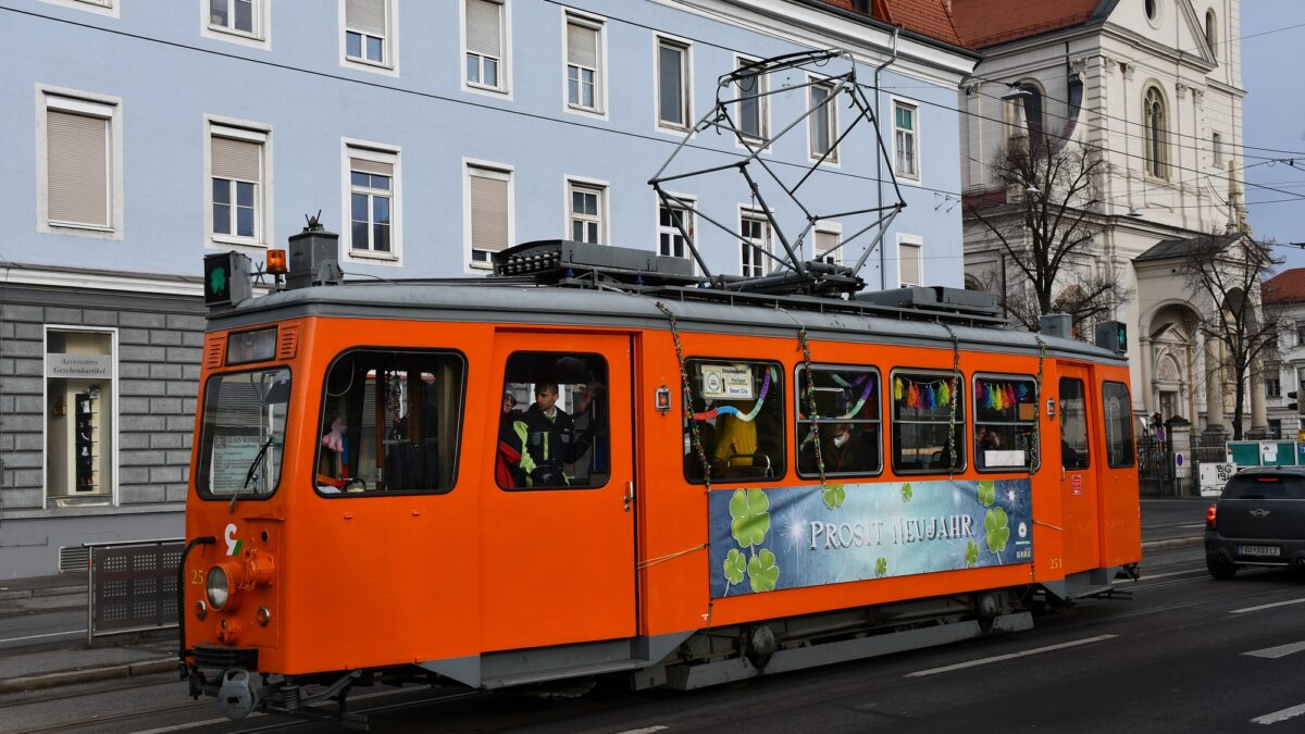 In rot gehaltene Silvesterbim fährt durch Graz. Man sieht im Inneren festliche Dekoration.