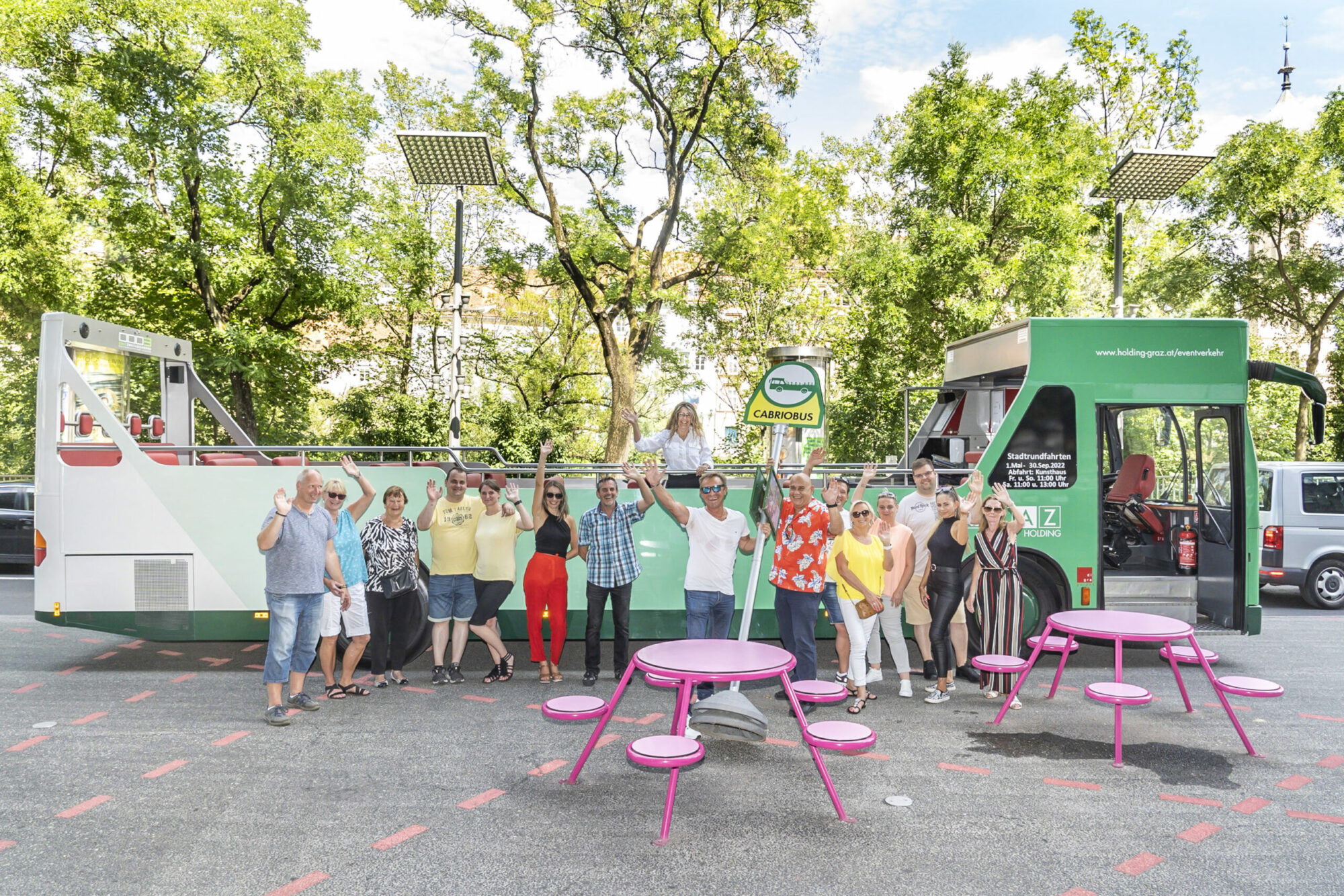 A group of people stand in front of a green Graz Linien CabrioBus with the text "Carriobus" on a sign.
