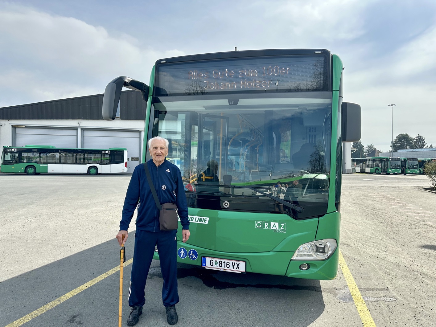 Johann Holzer vor grünem Graz Linien-Bus mit Inschrift "Alles Gute zum 100er Johann Holzer"