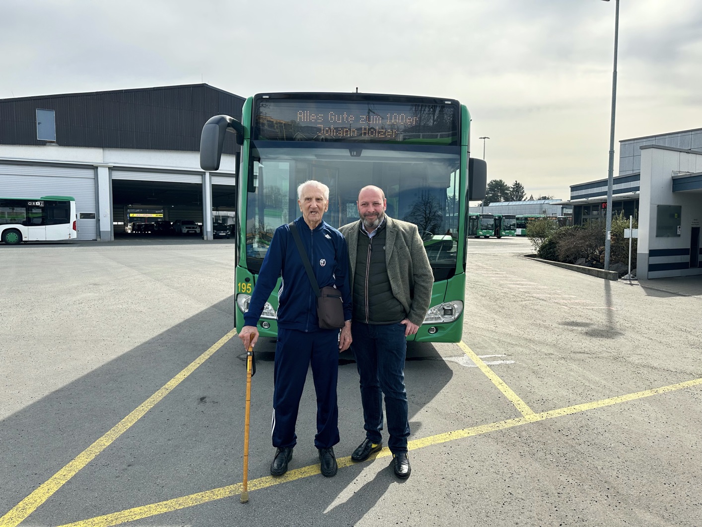 Johann Holzer und Mark Perz vor einem Bus mit der Inschrift "Alles Gute zum 100er Johann Holzer"