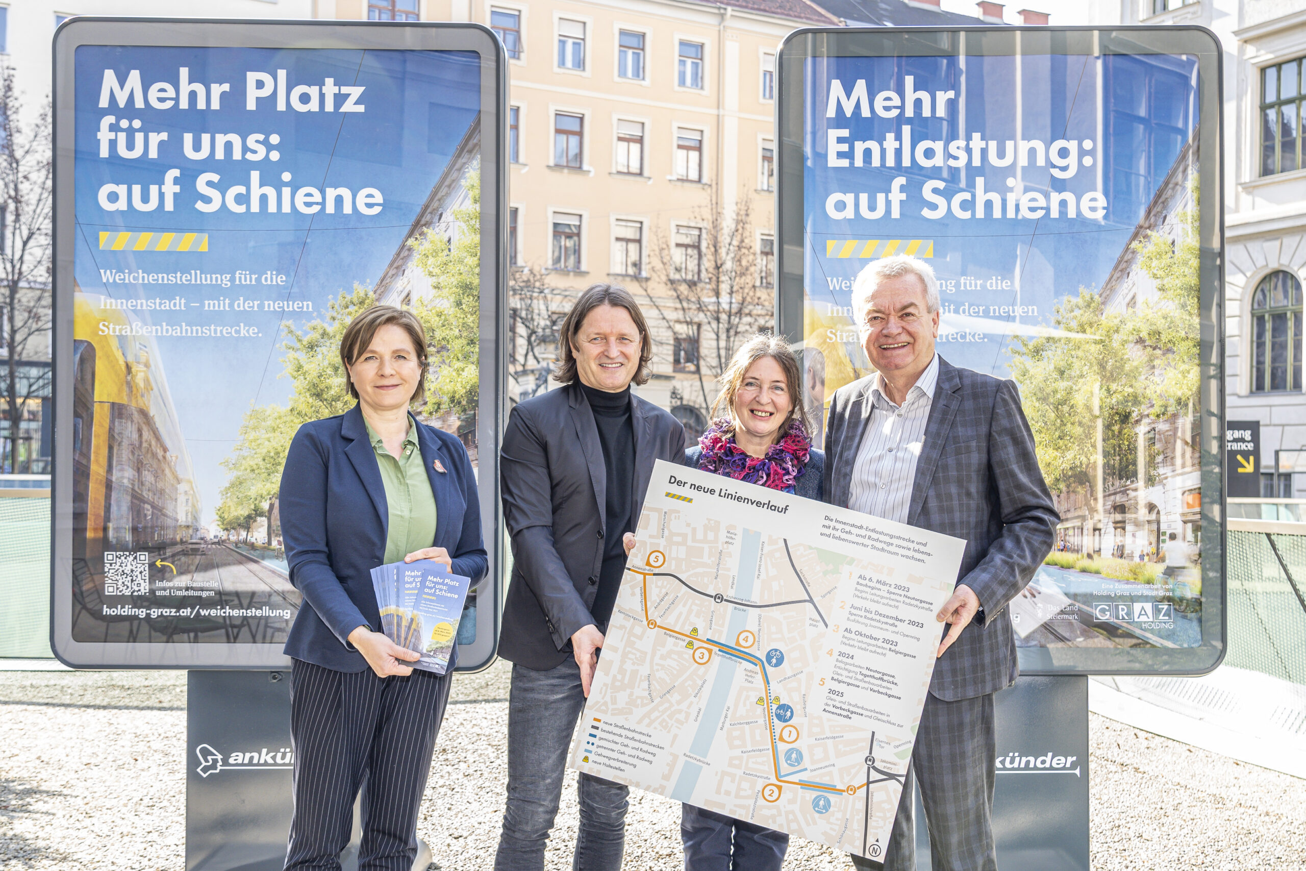 Vier Personen präsentieren den neuen Linienverlauf der Straßenbahn vor Plakaten in Graz.