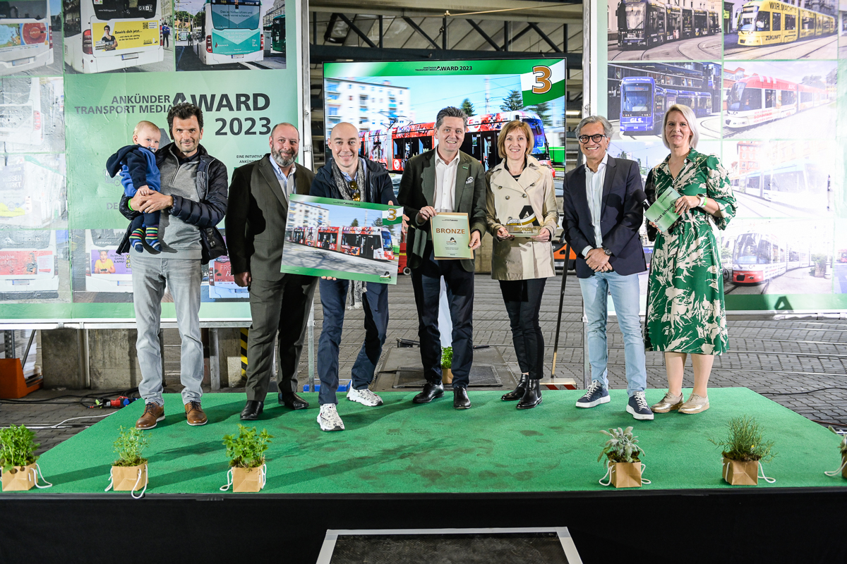 Sechs Personen auf Bühne vor Banner mit Text "Ankünder Transport Media Award 2023".