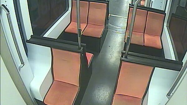 Innenansicht einer Straßenbahn mit orangefarbenen Sitzpolstern und schwarzem Boden.