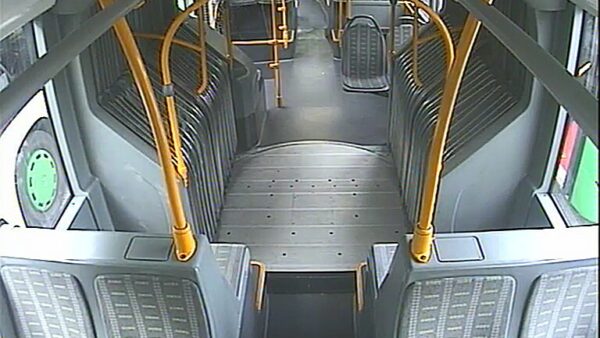 Innenansicht eines leeren Busses mit gelben Haltestangen und gestreiften Sitzpolstern.