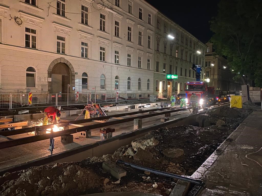 Nächtliche Gleisbauarbeiten in der Neutorgasse mit Arbeitern und beleuchteter Baustelle.