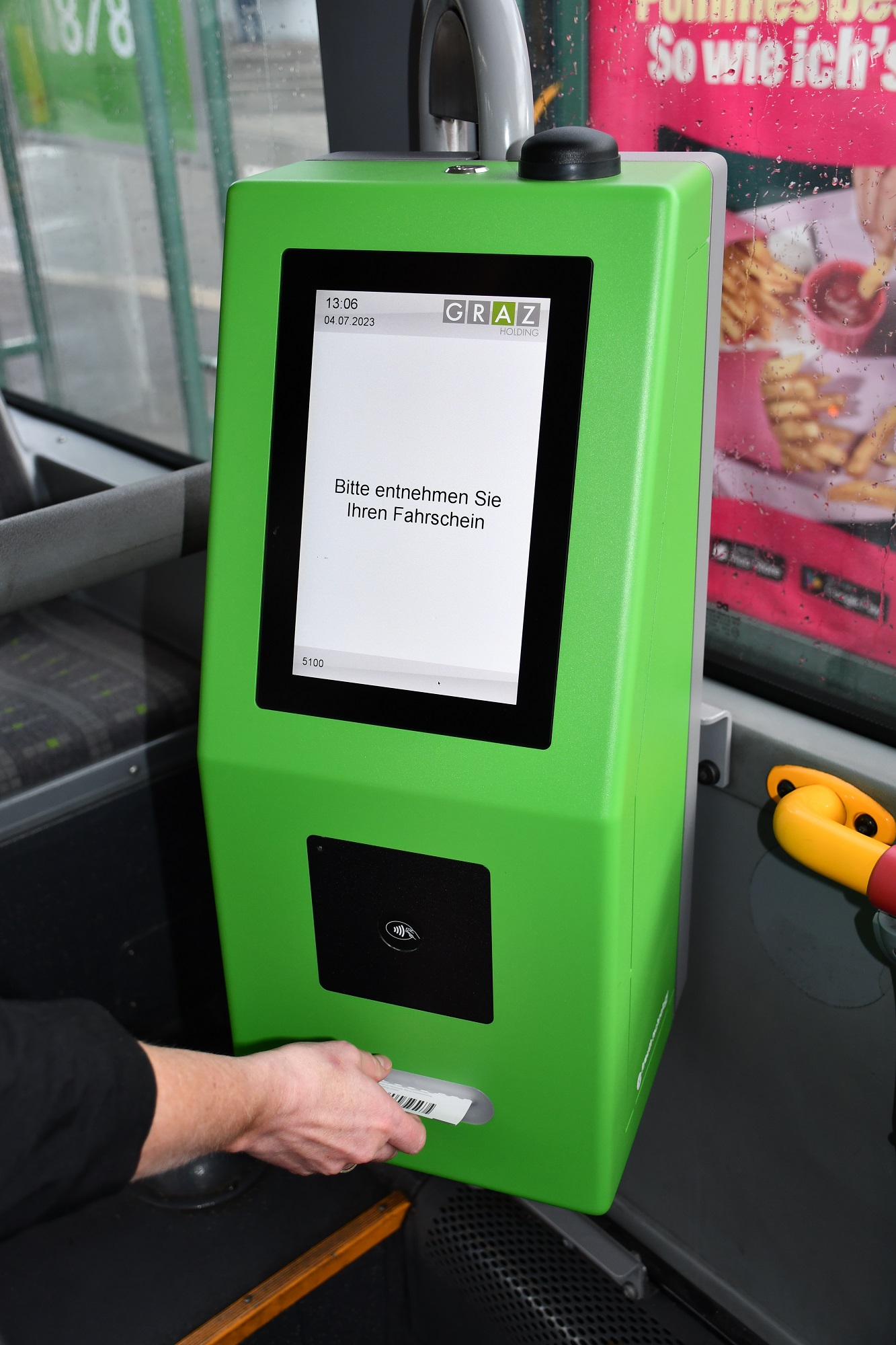 Fahrscheinautomat in einem Bus der Graz Linien. Hand entnimmt Fahrschein
