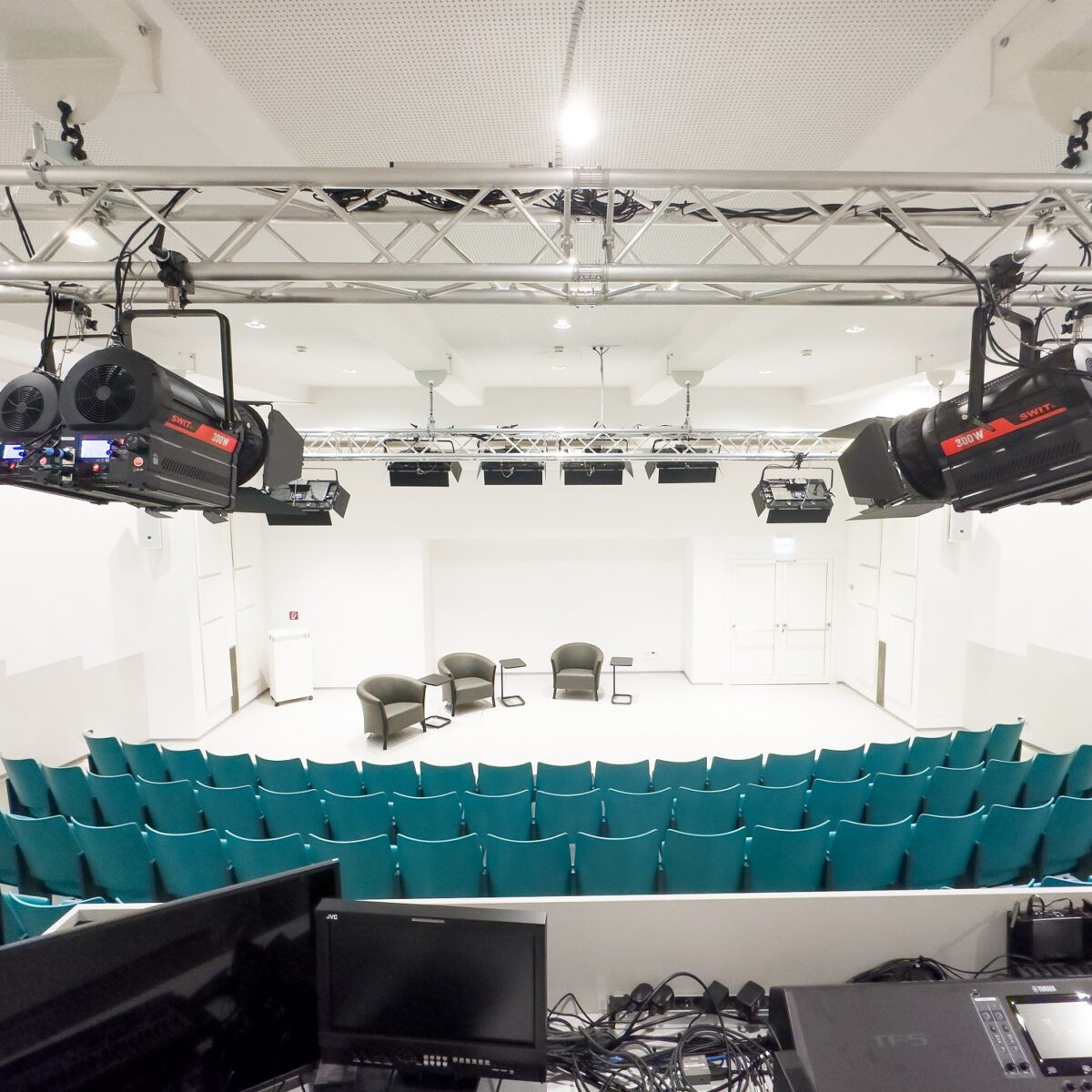 Moderner Multifunktionsraum mit Sitzreihen, Bühne, Beleuchtungstechnik und Steuerpult