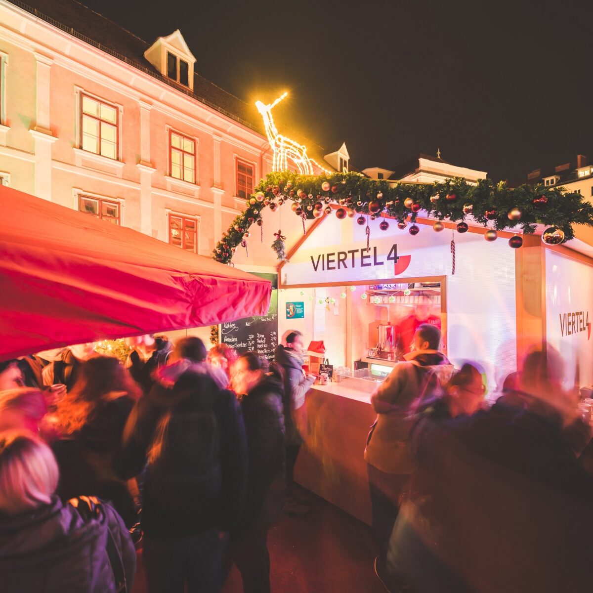 Menschen genießen Winterlounge mit Weihnachtsdekoration und beleuchtetem Verkaufsstand.