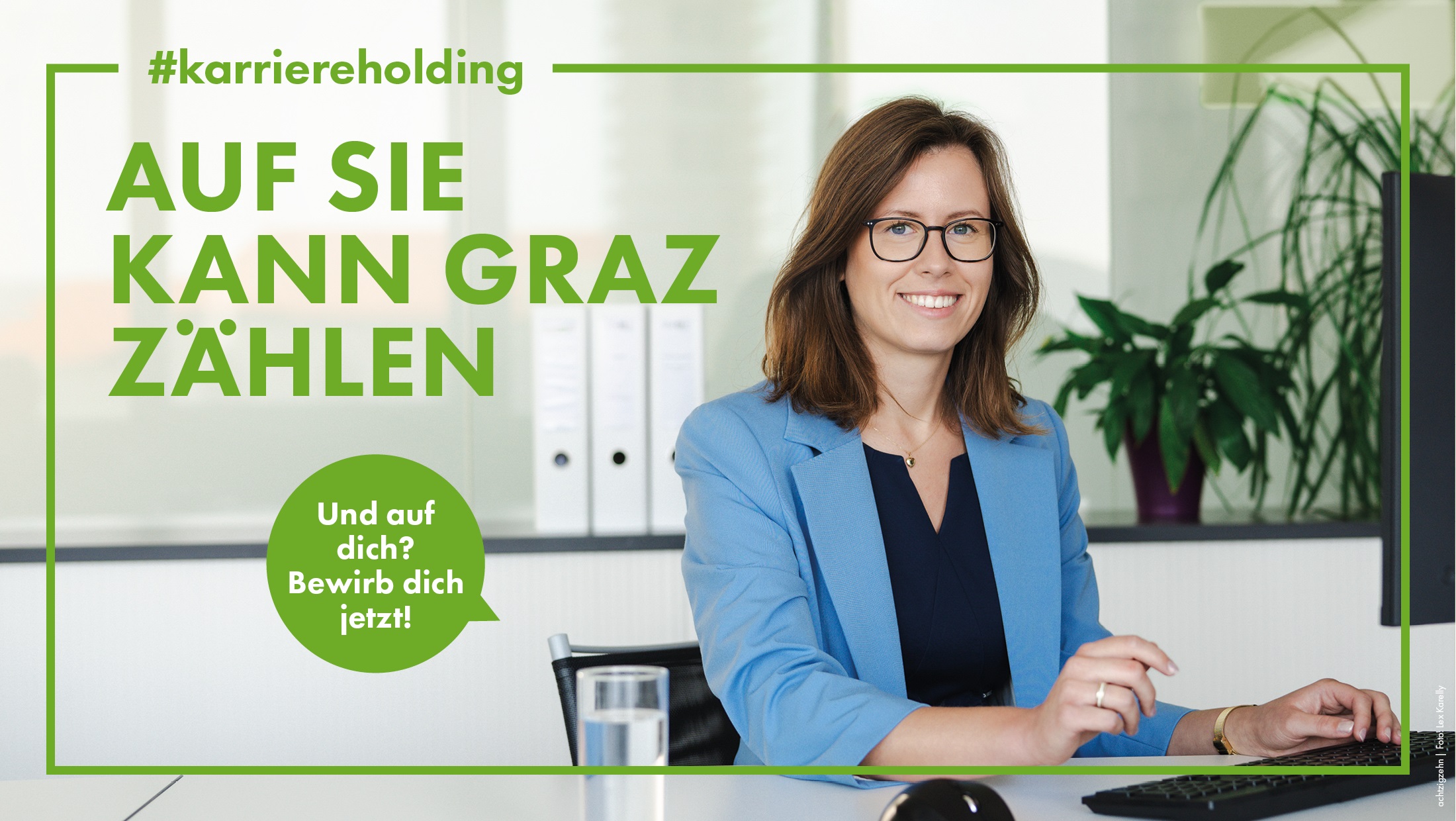 Lächelnde Frau im Büro, in blauem Blazer, arbeitet am Computer; Text: "Auf sie kann Graz zählen"
