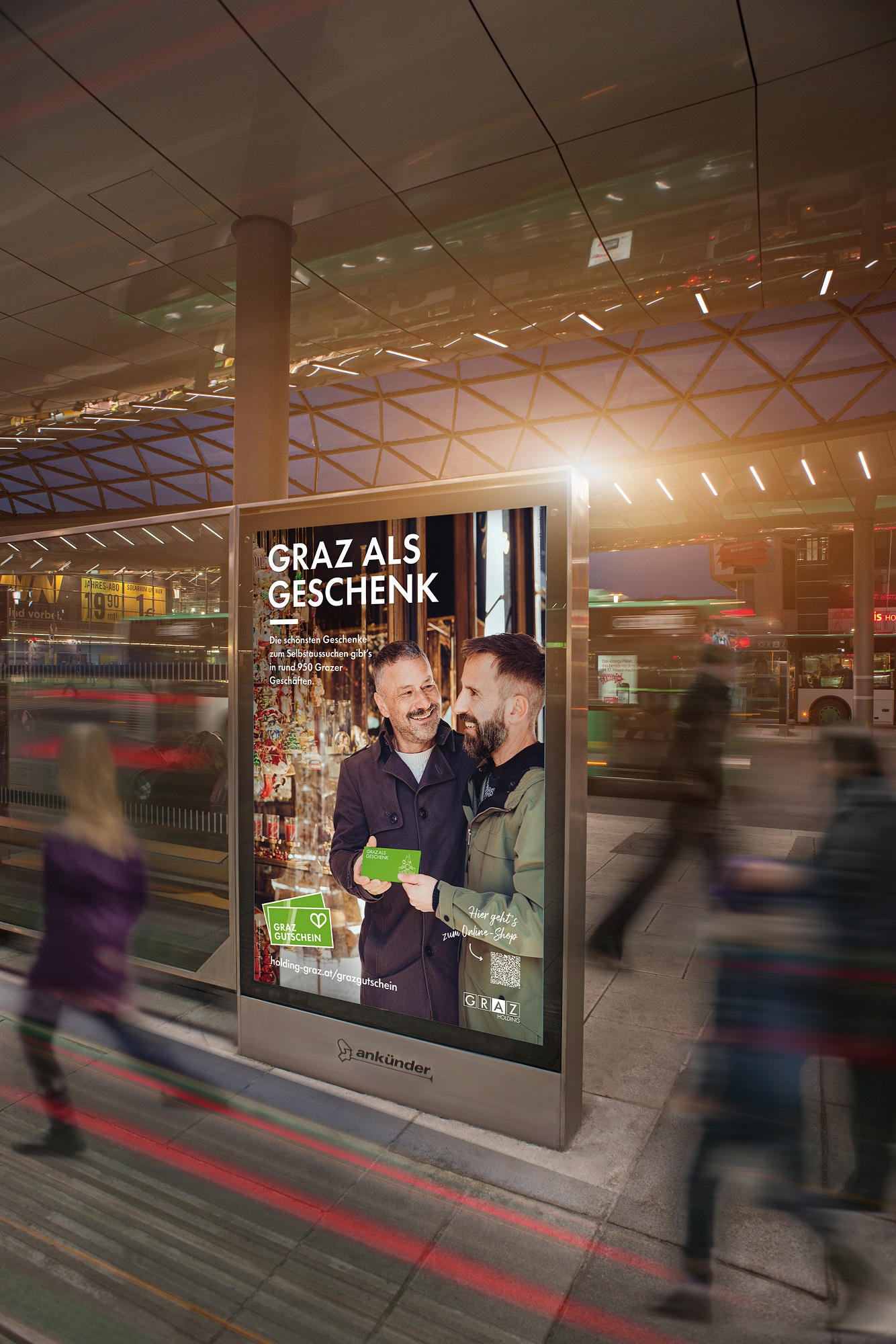 Straßenplakat mit Aufschrift "Graz als Geschenk" und zwei Männern, die sich "Graz Gutschein" schenken.