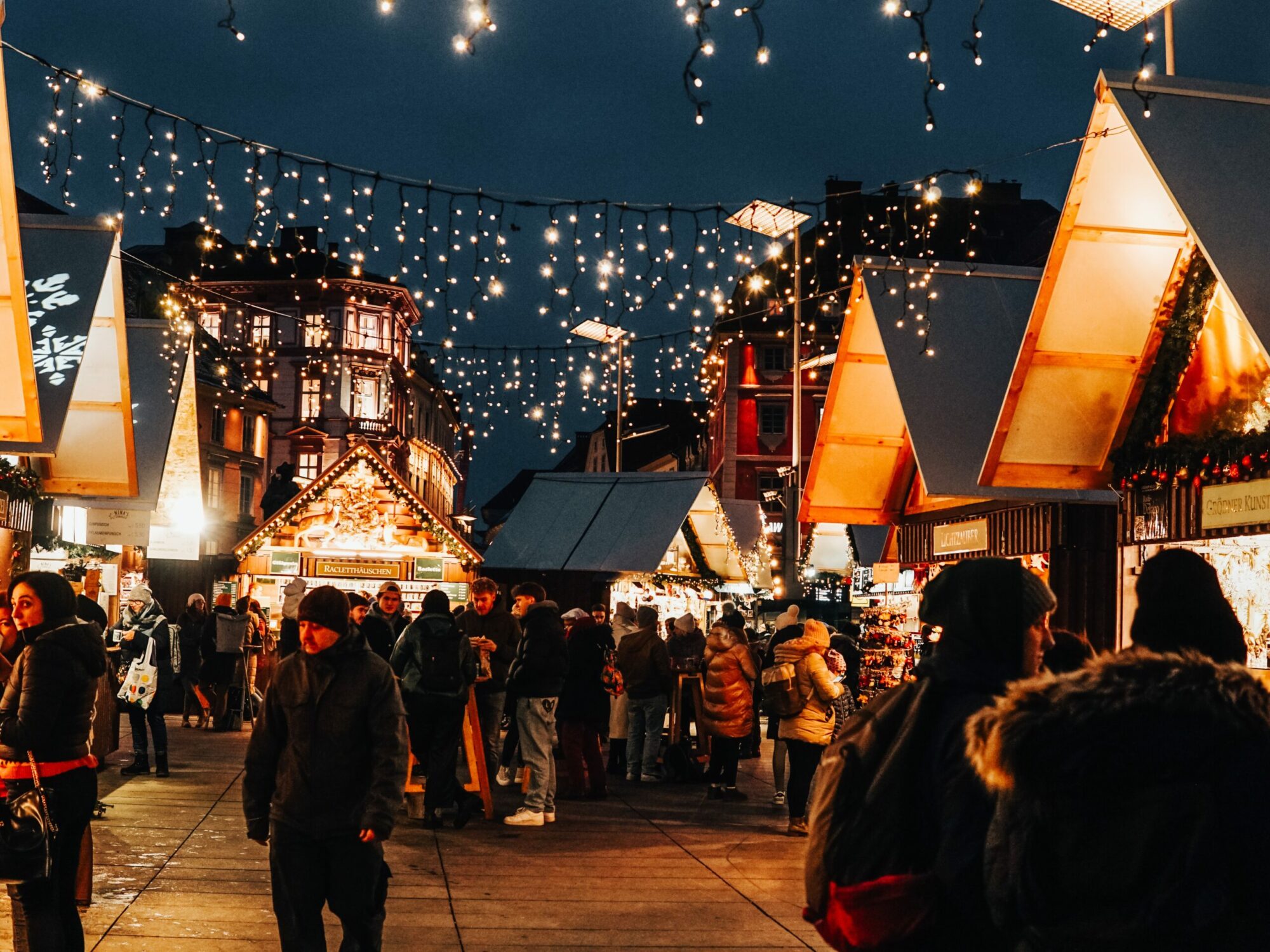 Beleuchteter Weihnachtsmarkt in Graz mit vielen Menschen.