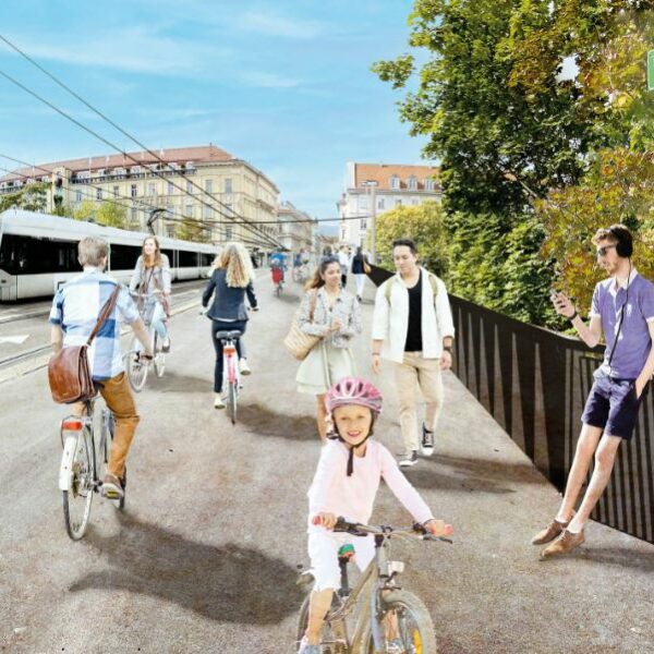 People bike and walk on a street with a tram, sign reads: "Tegetthoffbrücke"