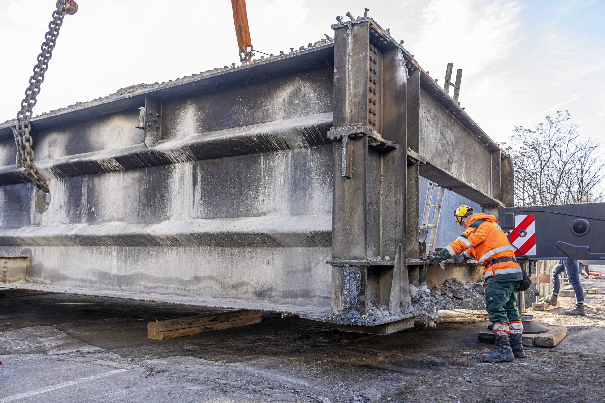 Ein Arbeiter in Arbeitsmontur inspiziert Teil der Tegetthoffbrücke, der von Kran angehoben wird.