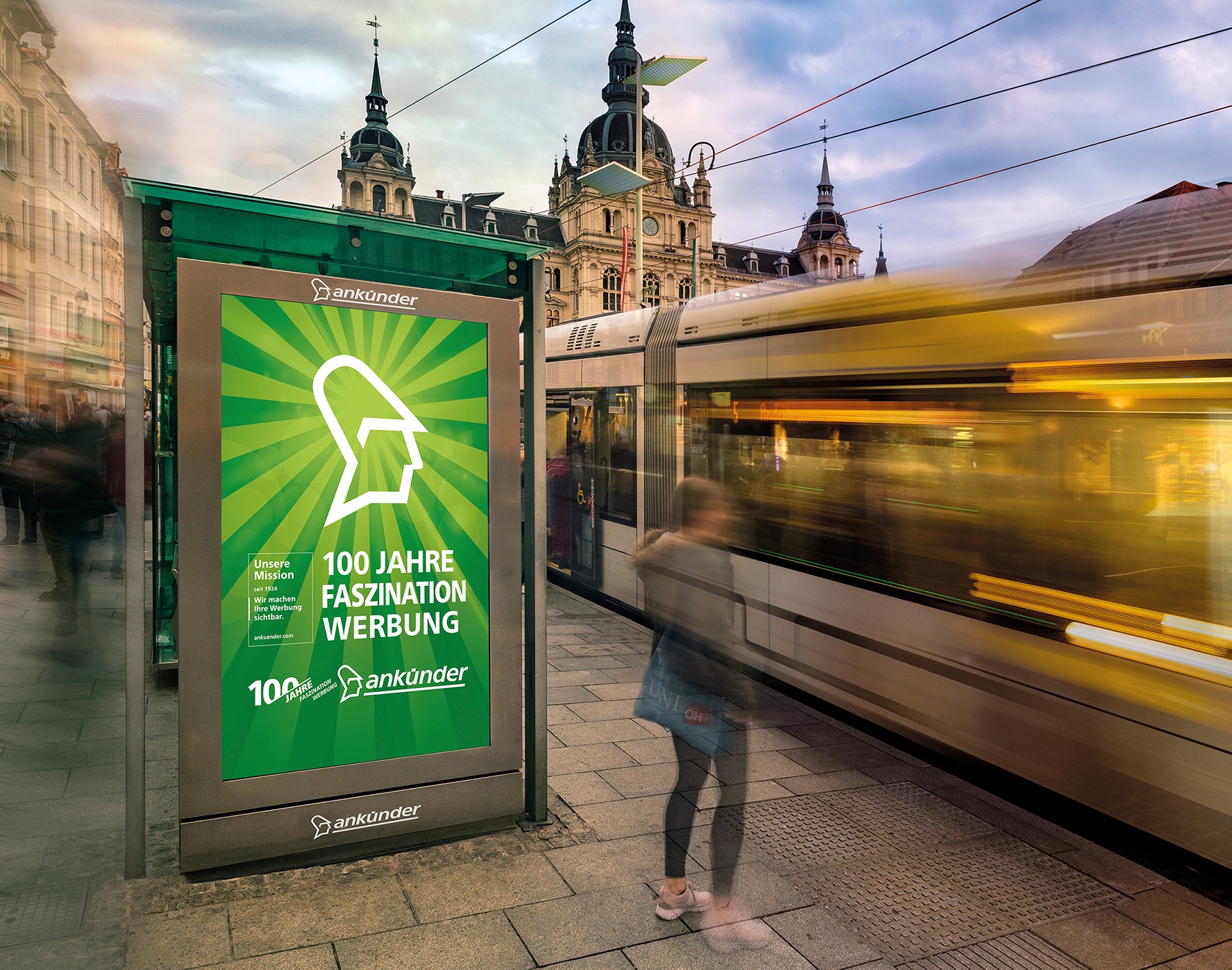 Fahrende Straßenbahn am Hauptplatz in Graz, vorne Plakat mit Slogan "100 Jahre Faszination Werbung"
