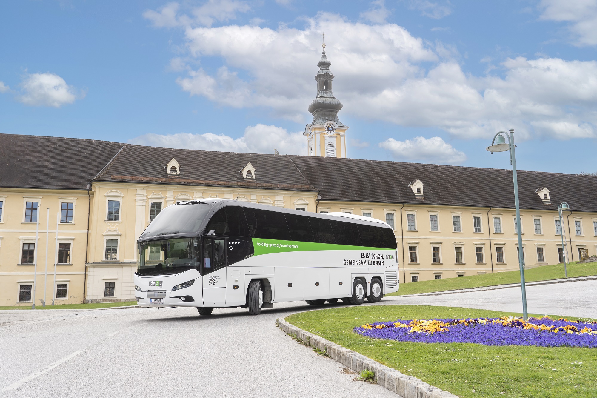 A white Graz Linien bus with the text "Es ist schön gemeinsam zu reisen" drives past Schloss St. Martin.
