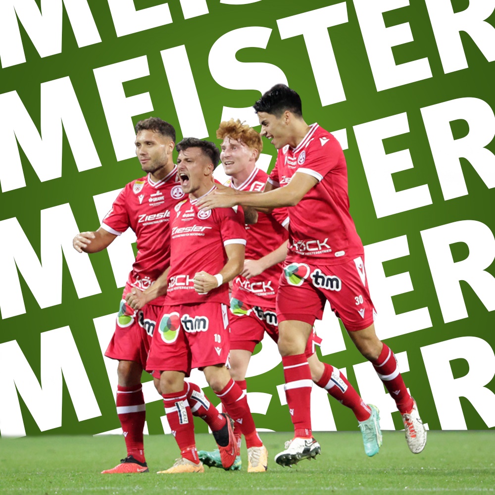 Vier GAK-Fußballspieler in roten Trikots feiern auf grünem Rasen vor Hintergrund mit Wort „Meister“.