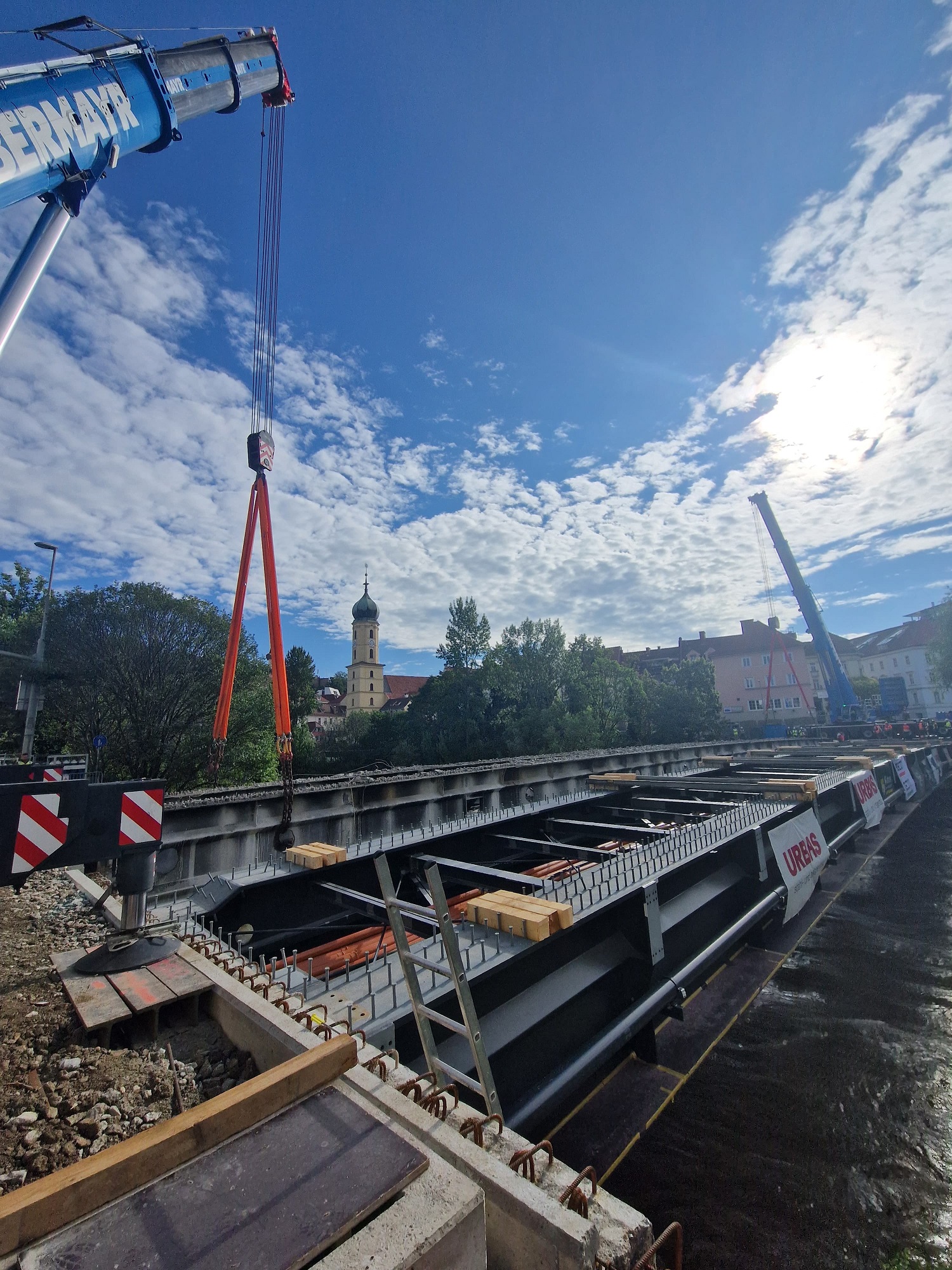 Ein Kran hebt bei sonnigem Wetter ein Brückenteil der Tegetthoffbrücke über der Mur in Graz.