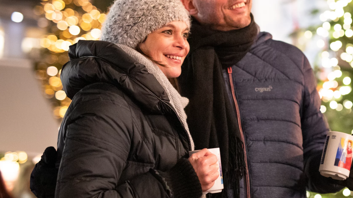 Ein Paar in Winterkleidung genießt Glühwein auf einem Weihnachtsmarkt.