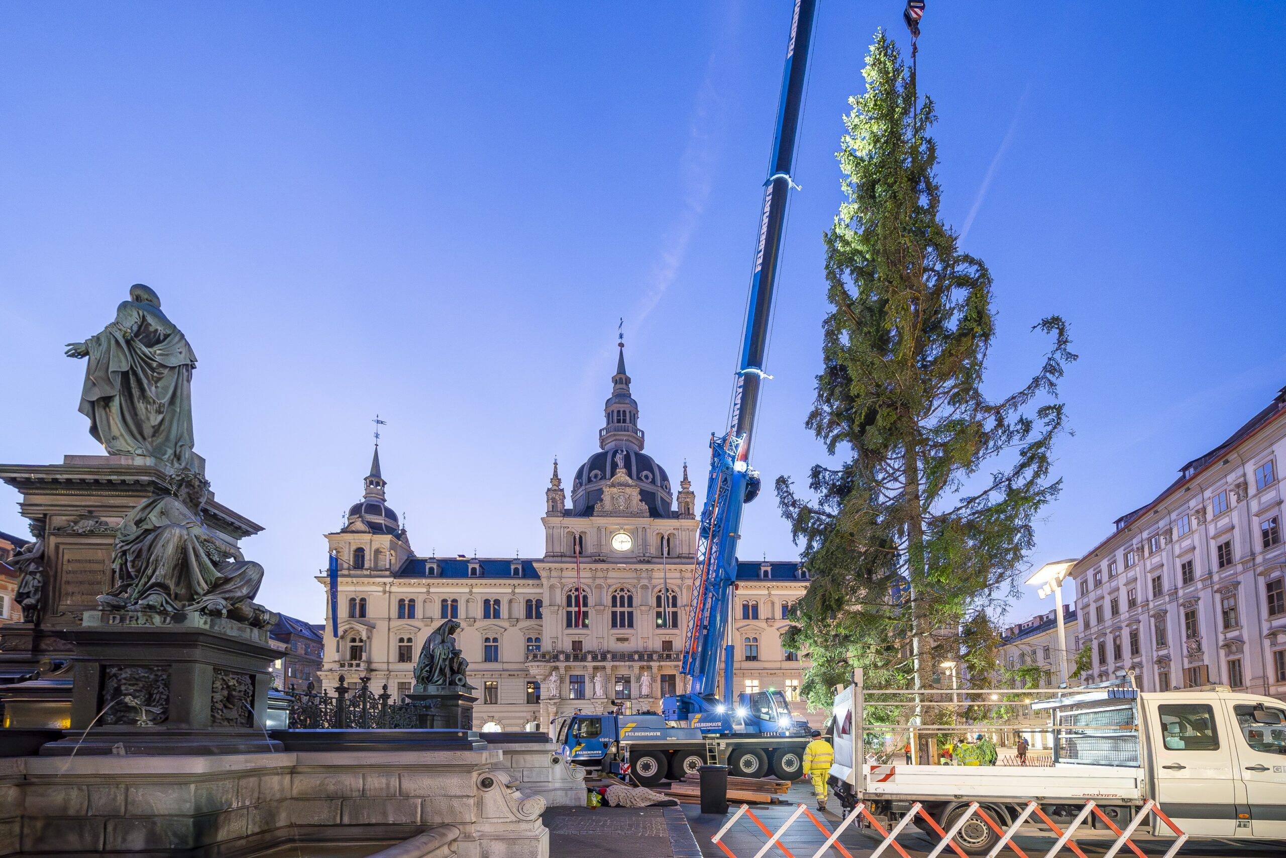 Ein Kran der Firma Felbermayr hebt einen Weihnachtsbaum auf dem Hauptplatz in Graz in die Höhe.