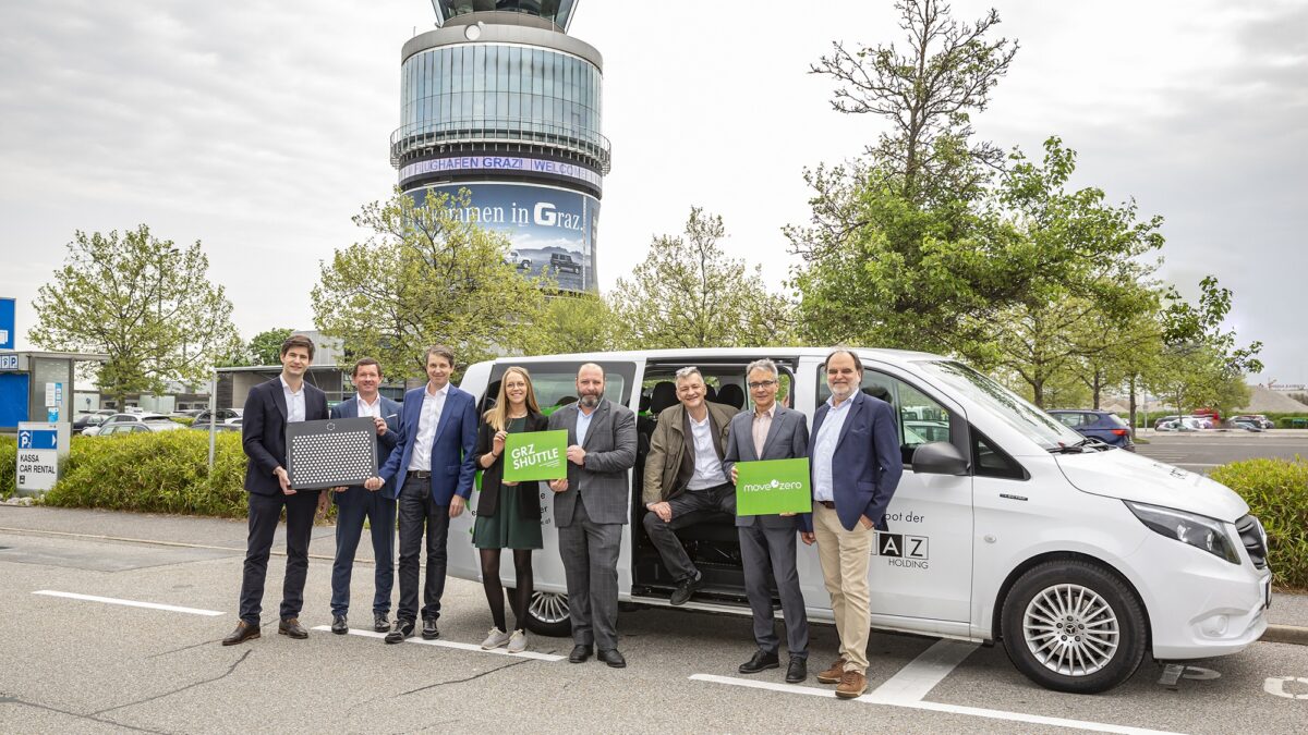 Vier Personen vor Fahrzeug am Flughafen Graz. Auf Schildern steht „GRZ Shuttle“ und „move zero“.