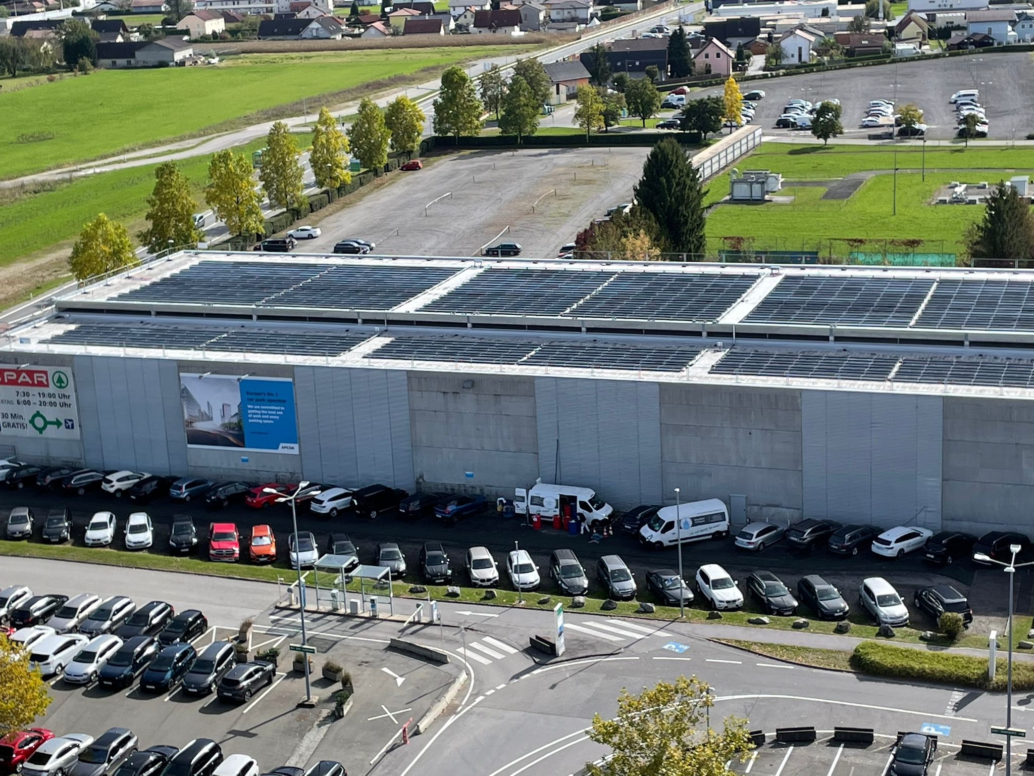 Ein Gebäude mit einer großen Photovoltaikanlage und einem Parkplatz davor.