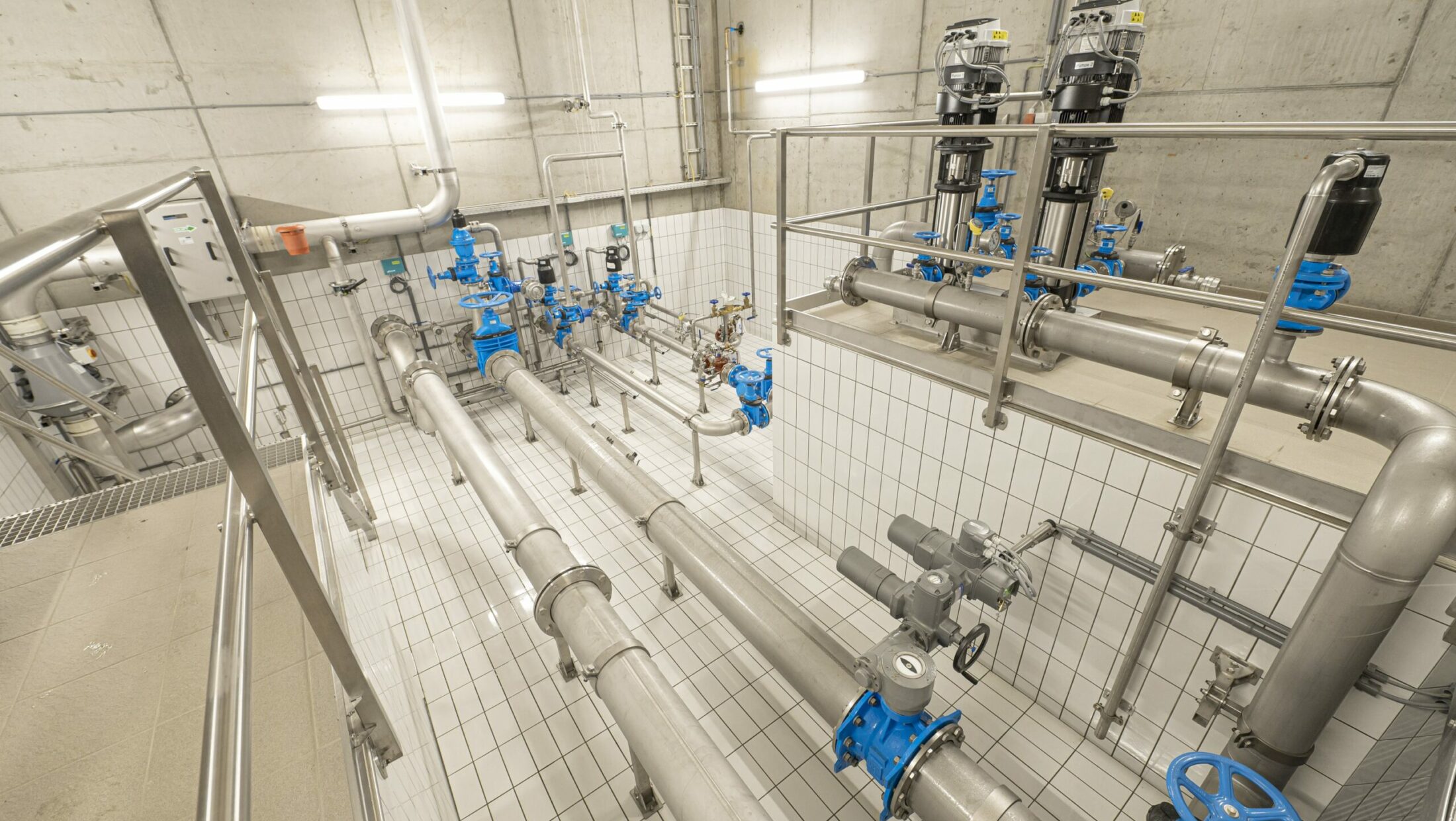 Industrielle Pumpen und Rohrleitungen mit blauen Ventilen in einem Technikraum