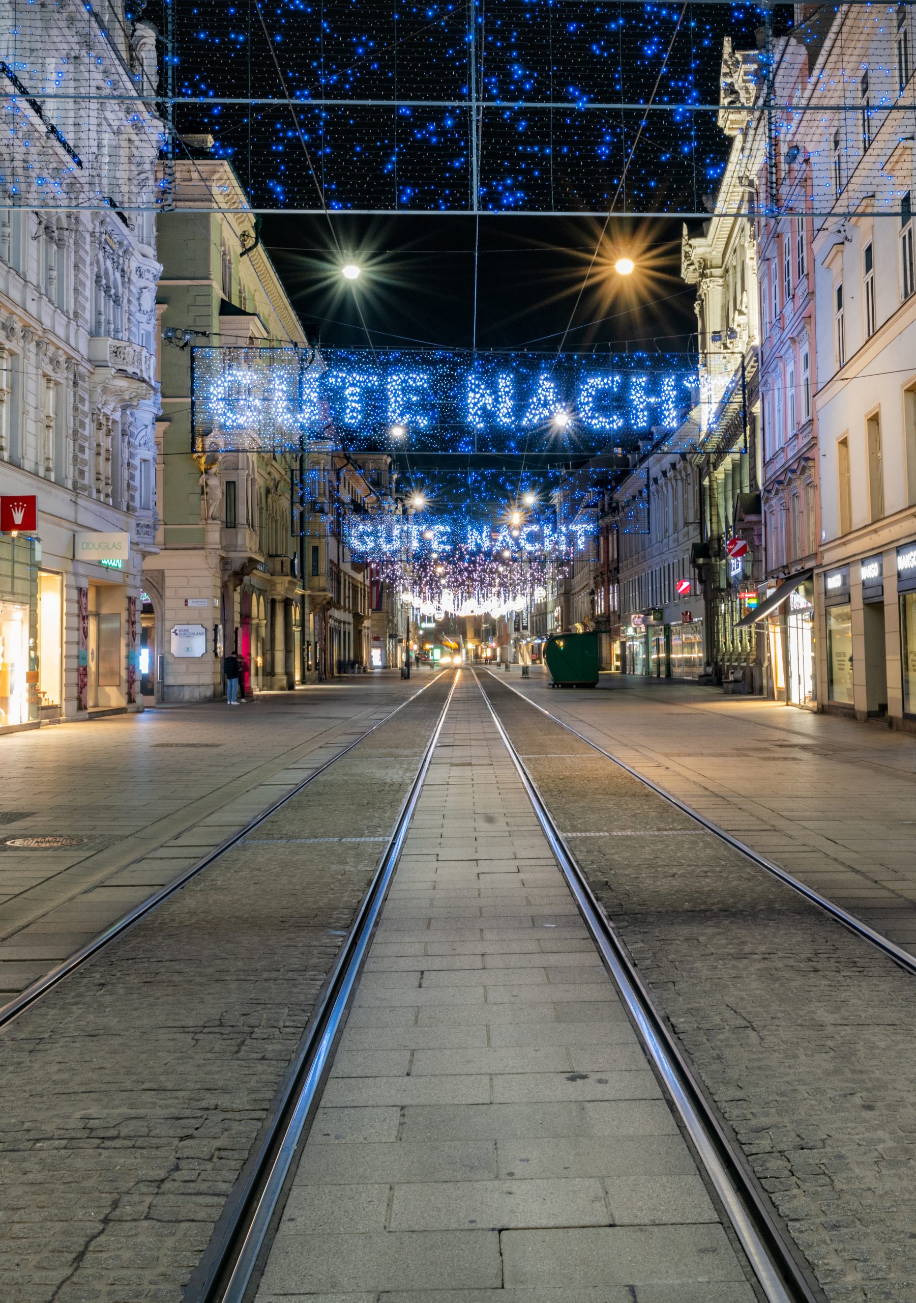 Leere Heerengasse mit Straßenbahngleisen und festlicher Beleuchtung, Schriftzug „Gute Nacht“.