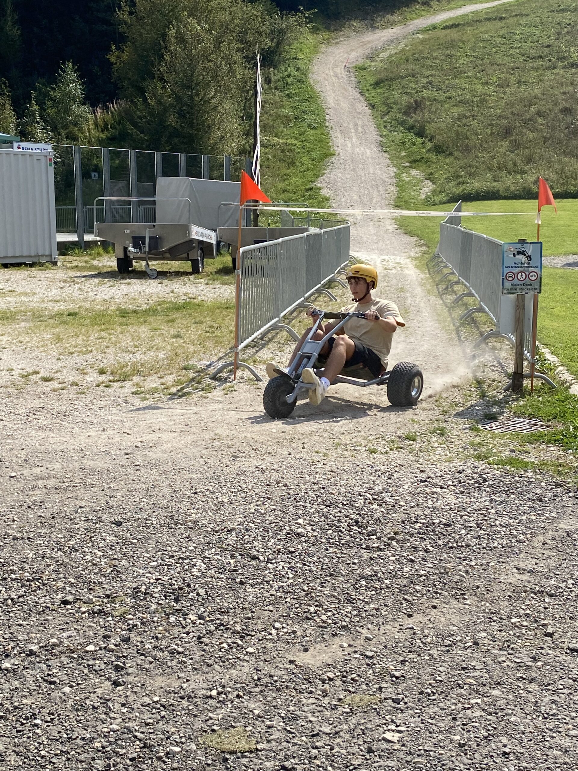 Ein Mann mit Helm fährt einen Go-Kart auf einer Schotterpiste bergab.