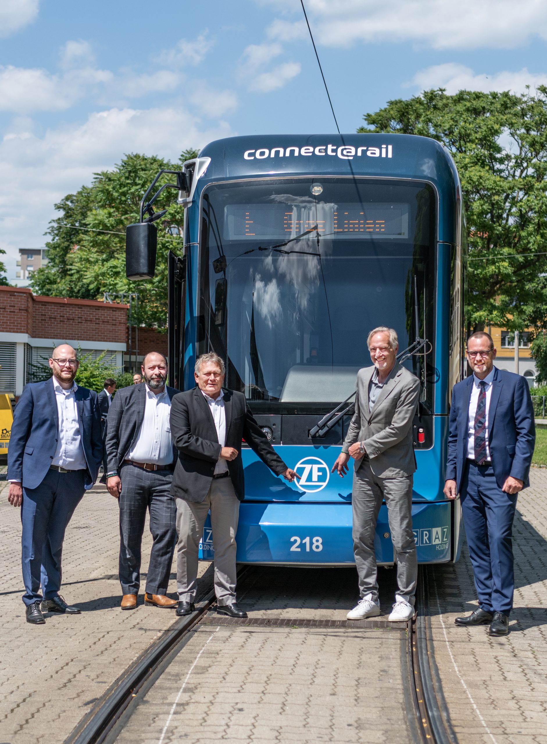 Fünf Personen stehen vor einer Straßenbahn im Design der Firma ZF