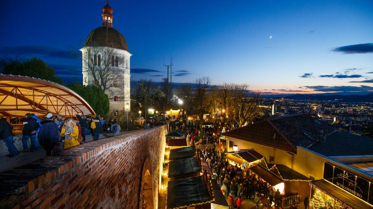 Blick auf den Grazer Schlossberg mit Weihnachtsmarkt bei Nacht.