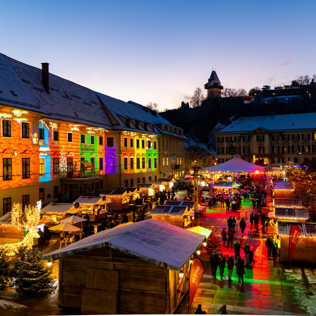Weihnachtsmarkt am Hauptplatz in Graz mit bunten Lichtern und dem Grazer Uhrturm.