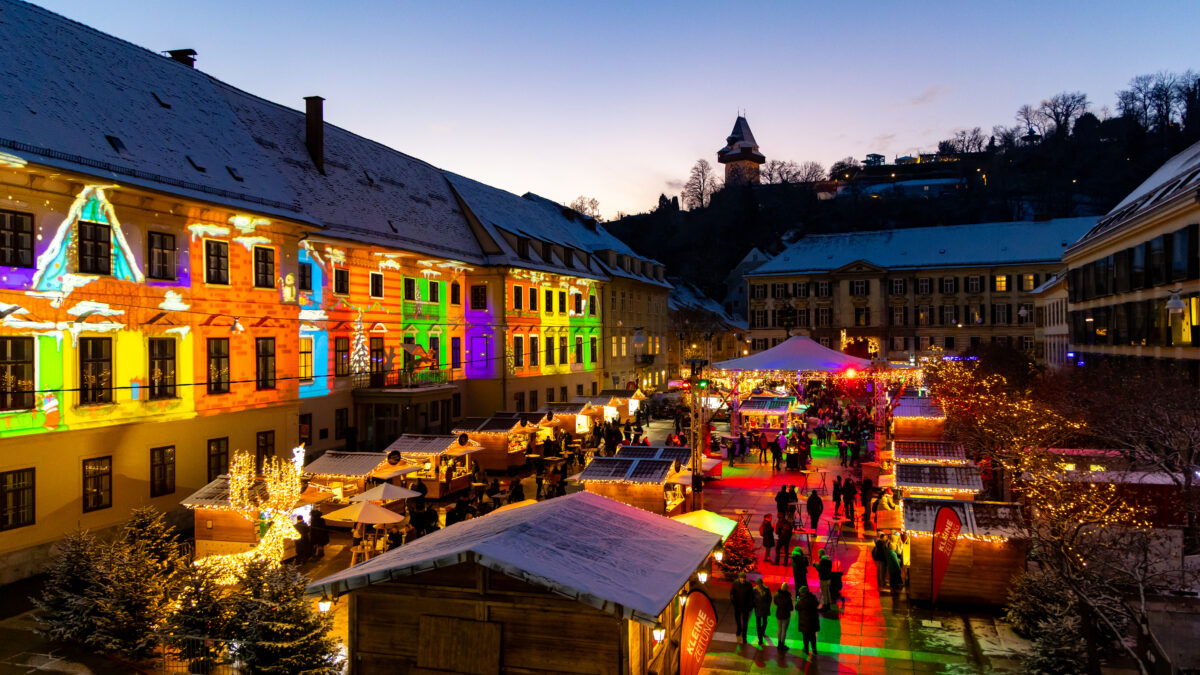 Weihnachtsmarkt am Hauptplatz in Graz mit bunten Lichtern und dem Grazer Uhrturm.