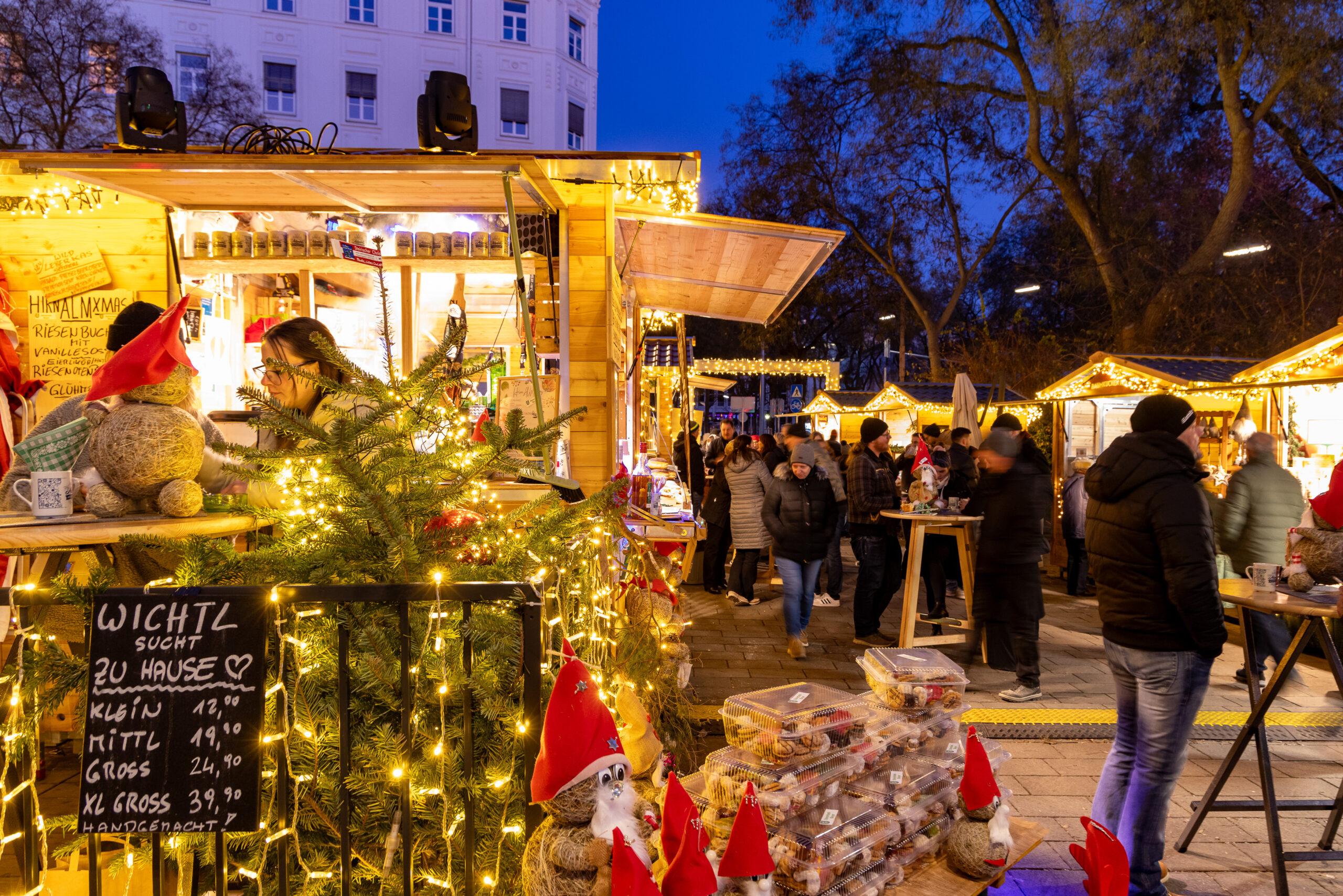 Christmas market in Graz. "Wichtl sucht zu Hause" sign. People.
