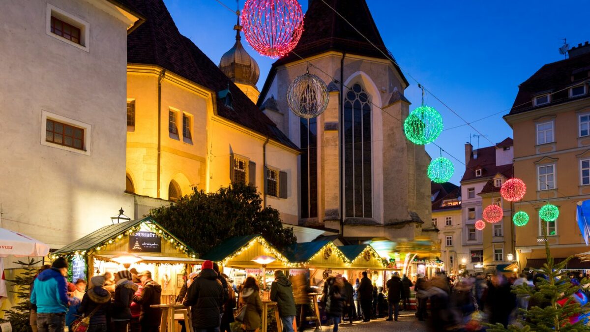 Weihnachtsmarkt in Graz bei Nacht mit Lichtern und Menschen.