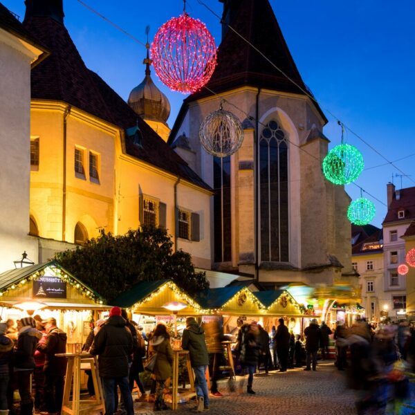 Weihnachtsmarkt in Graz bei Nacht mit Lichtern und Menschen.